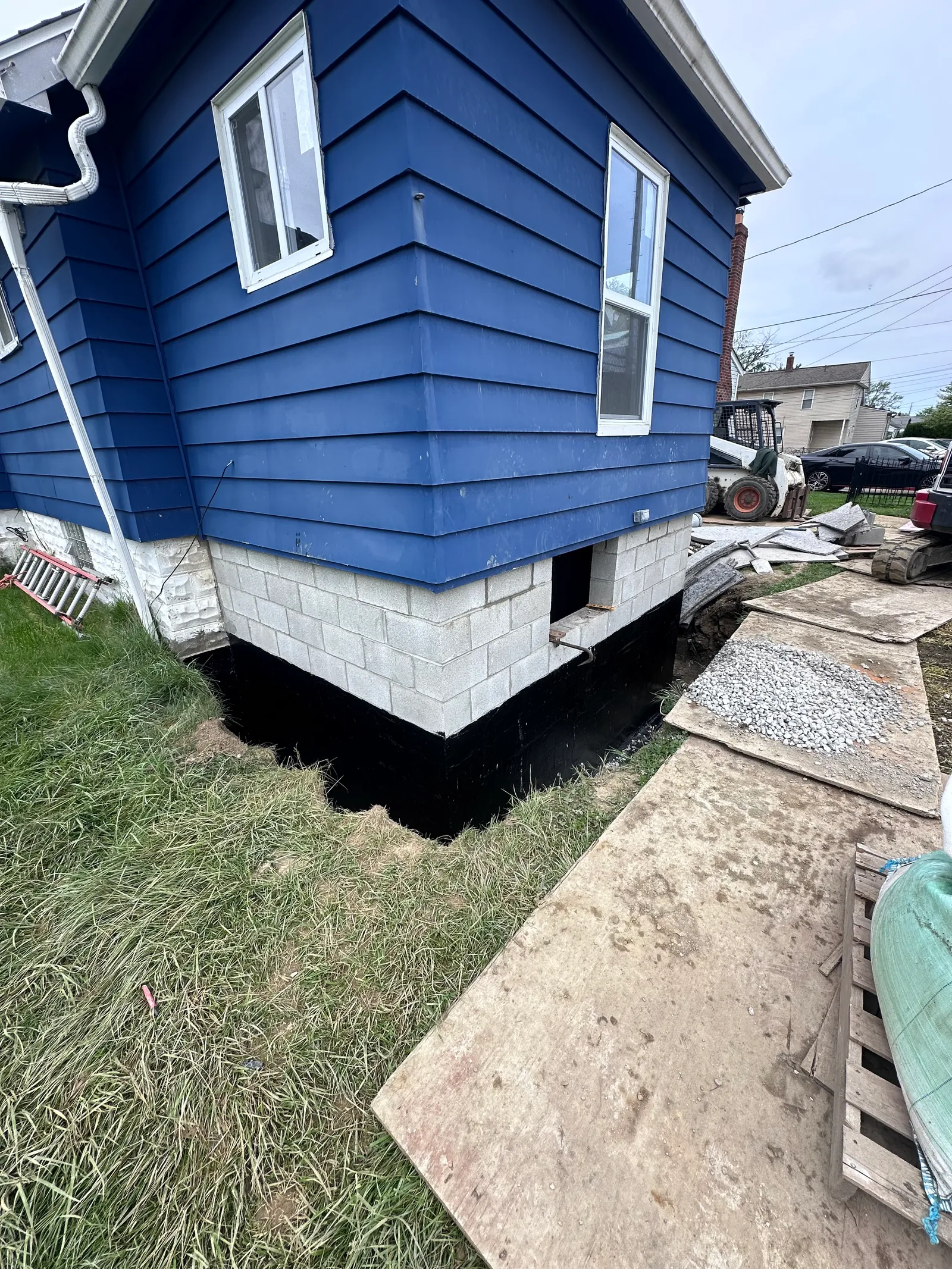 Completed waterproofing membrane application with paver walkway along foundation