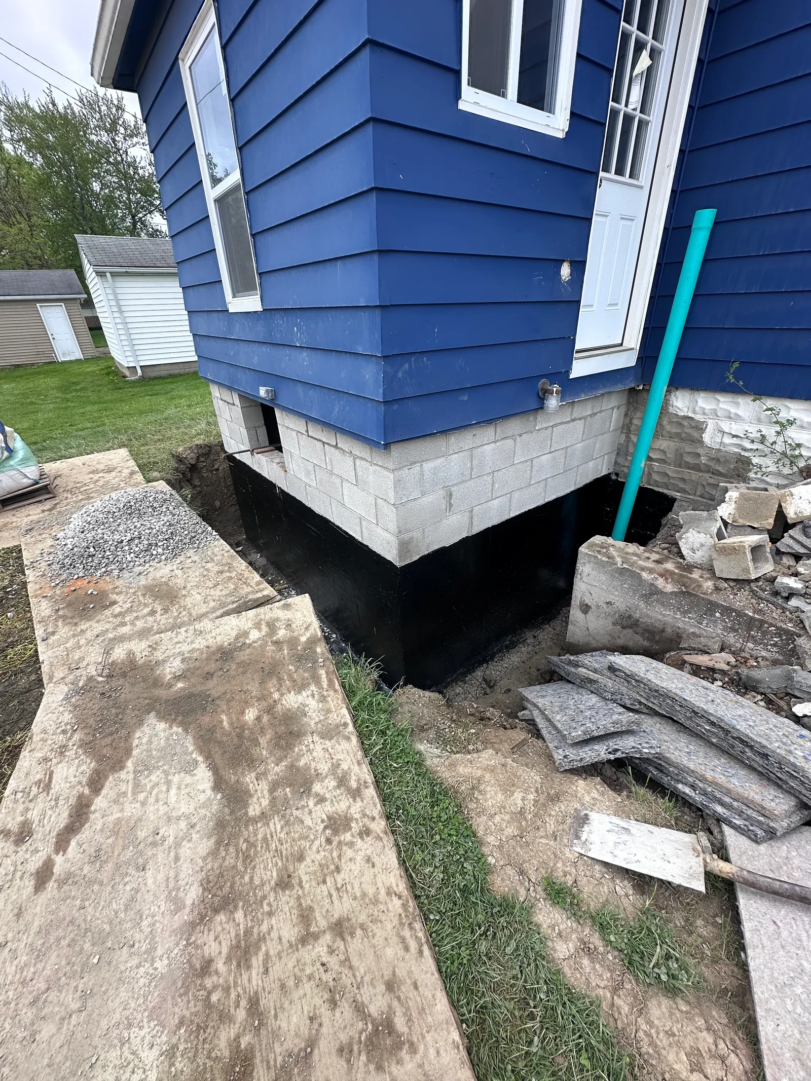 Black waterproofing membrane and PVC drain pipe installed on foundation wall