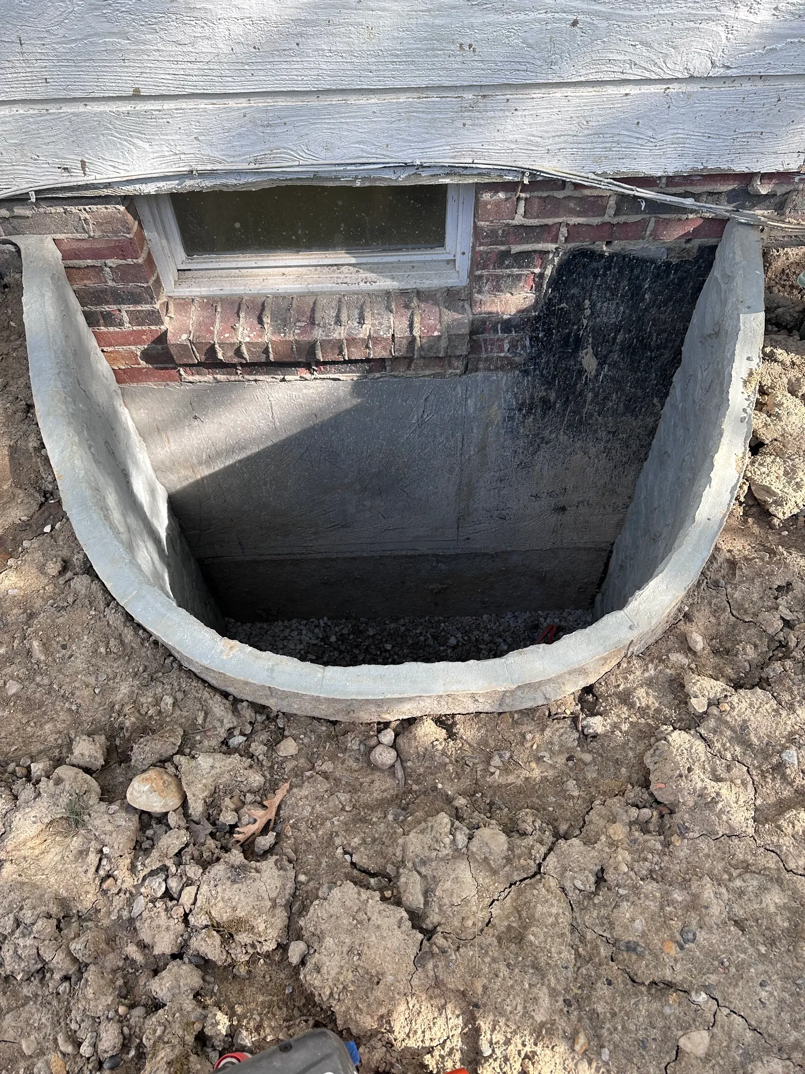 Window well installed against brick foundation wall for basement egress