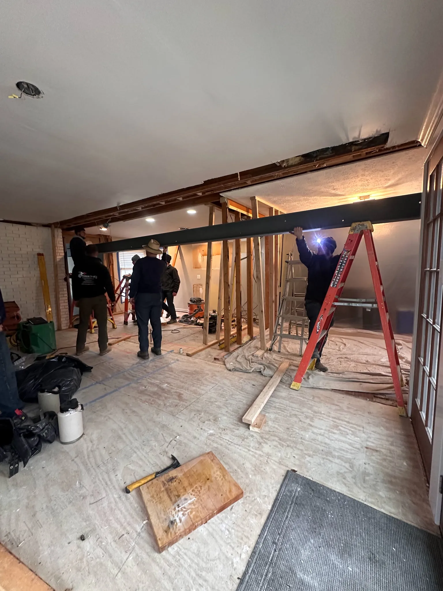 Structure Strong crew installing a steel I-beam during interior renovation