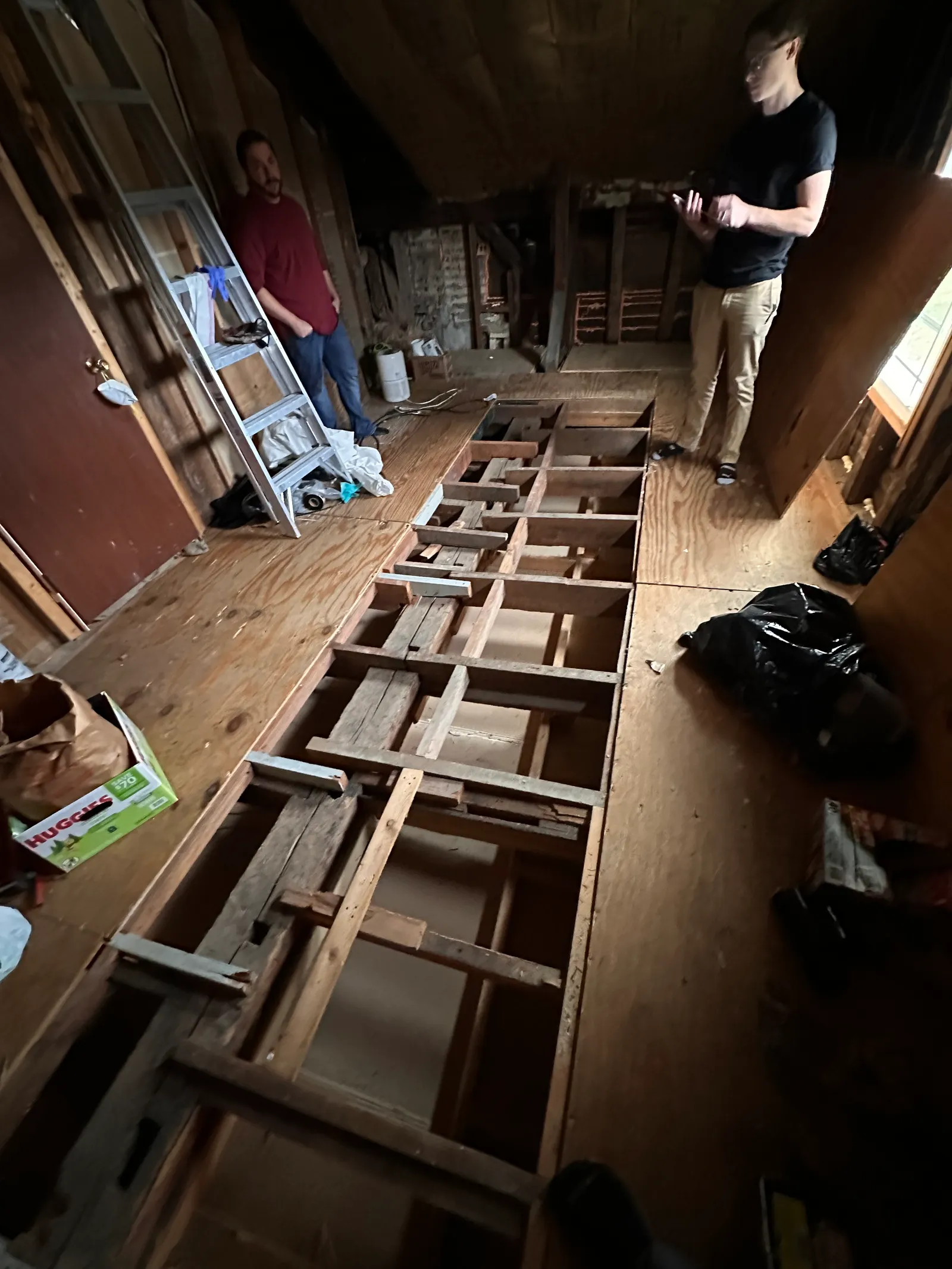 Workers at opened floor section with exposed joists during demolition