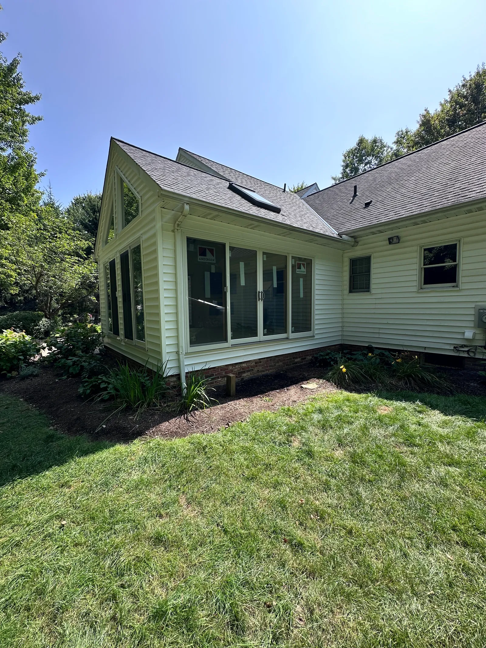 Workers framing a room addition with trusses and window openings
