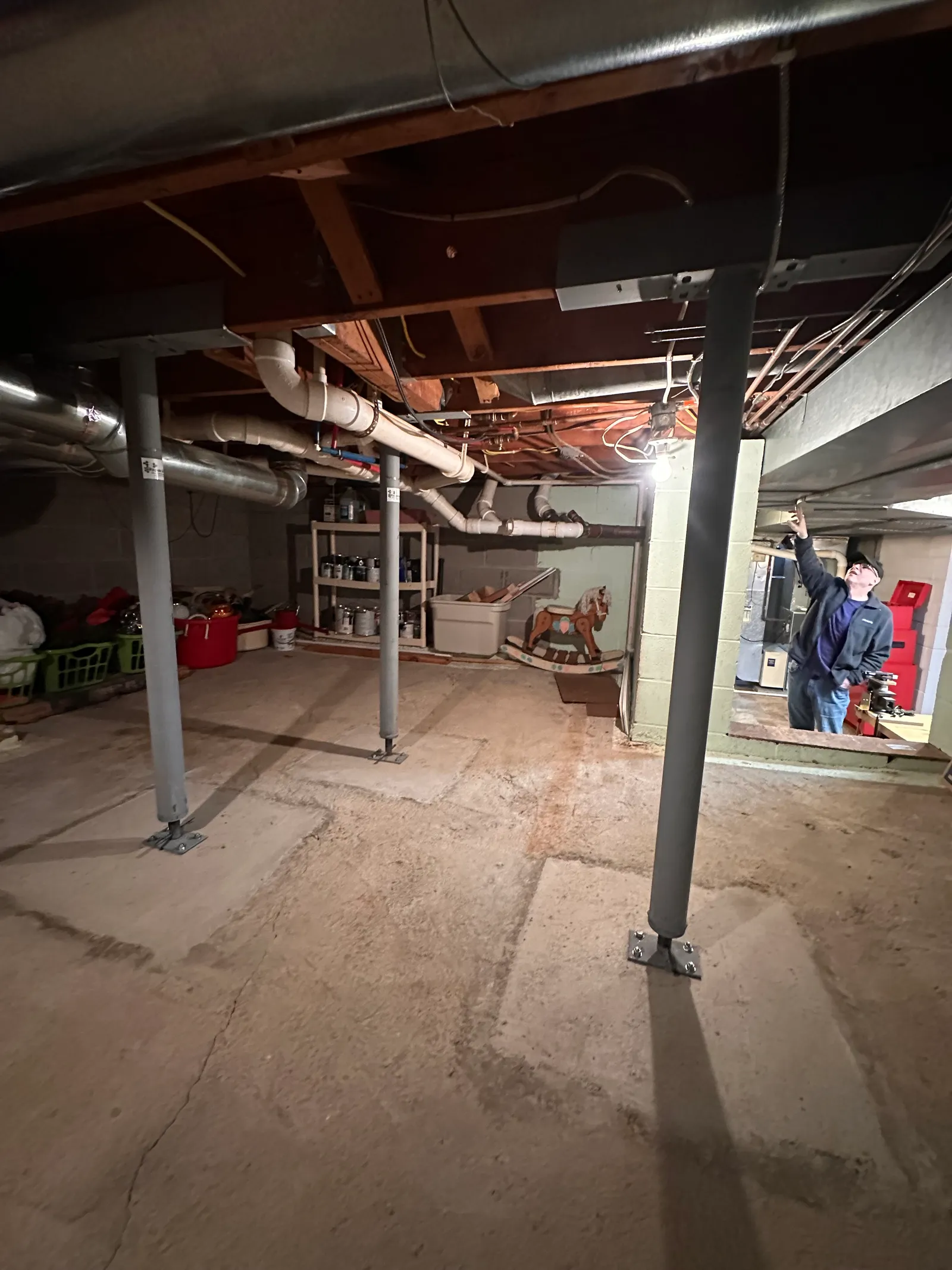 Worker inspecting steel column-to-beam connection in basement