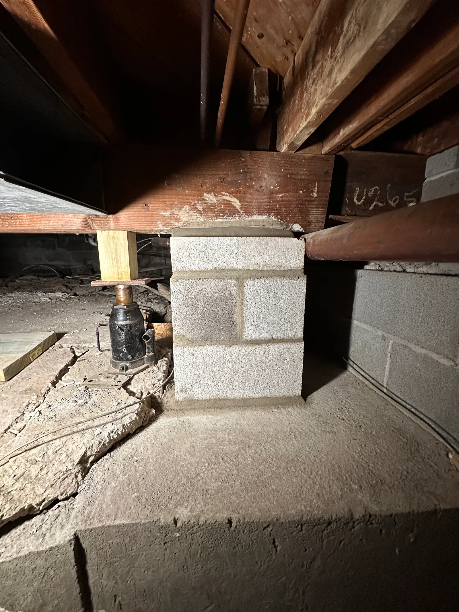 Screw jack providing structural support on CMU pier in crawlspace