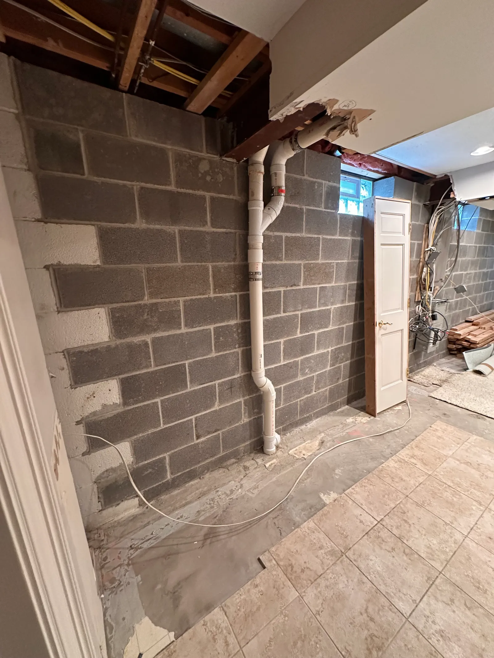 Interior PVC drain pipe installed along basement wall during drainage work