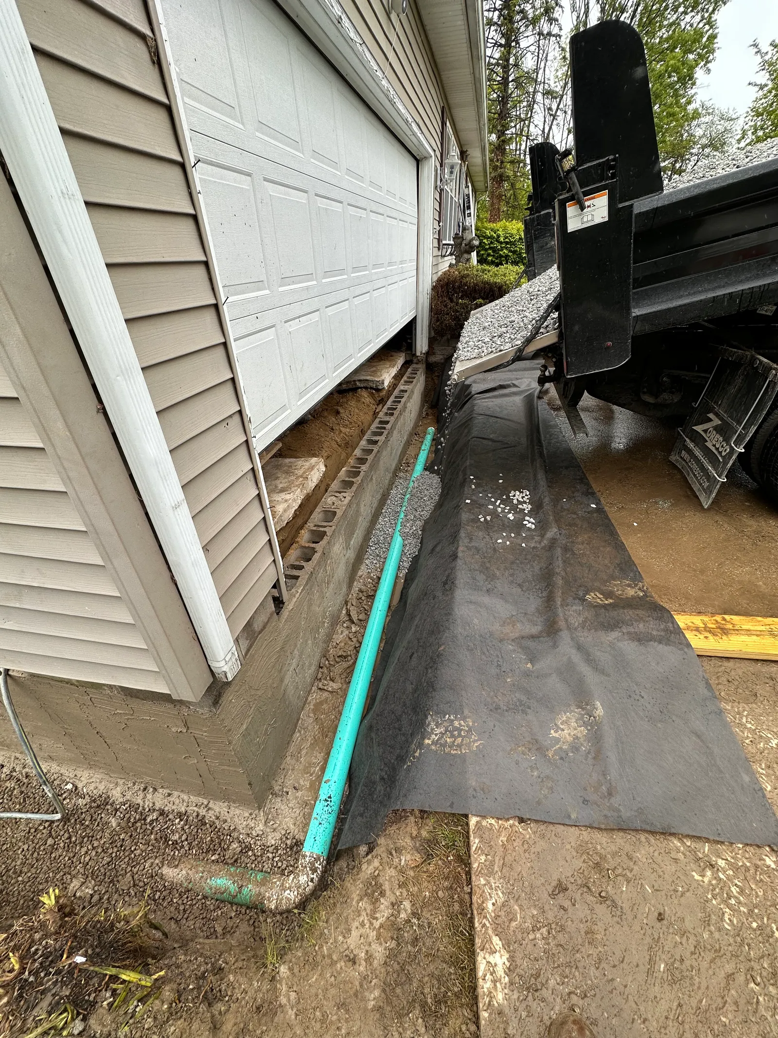 French drain with perforated pipe and geotextile fabric during gravel backfill