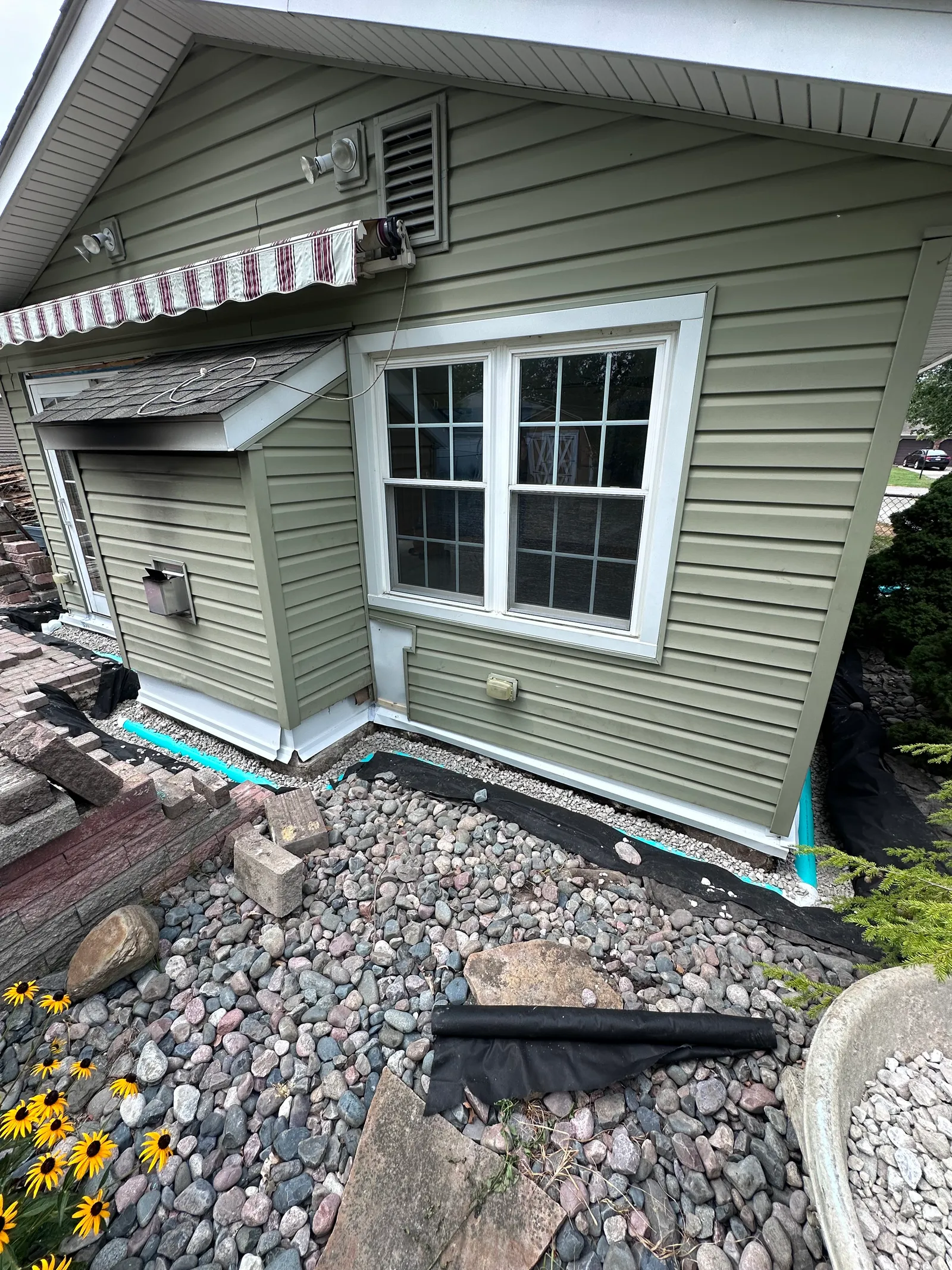 Completed foundation drainage with river rocks over landscape fabric