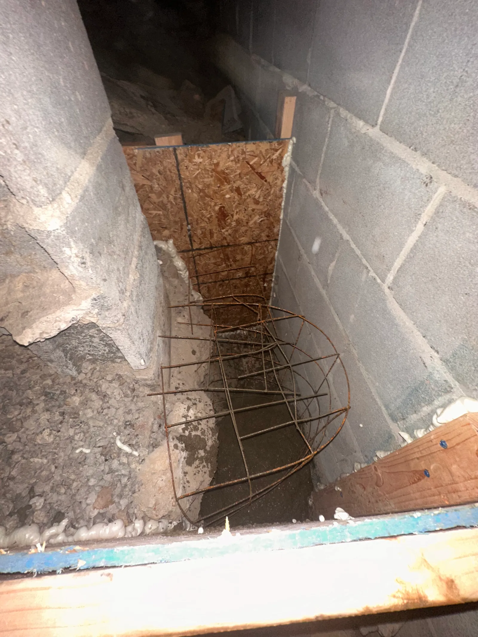Cylindrical rebar cage in excavated pier area between block foundation walls