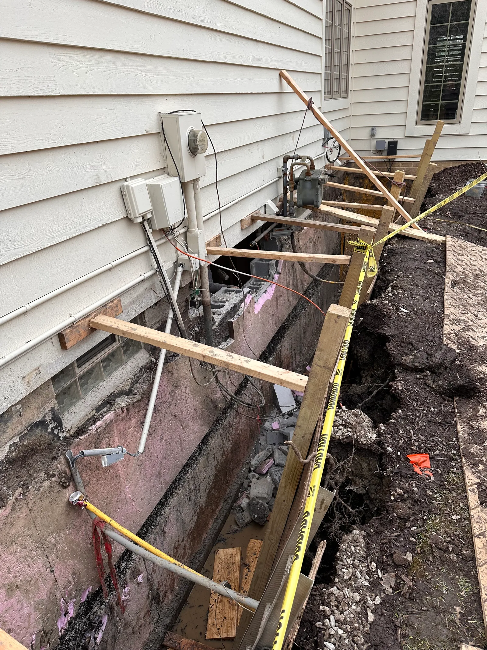 Foundation excavation with caution tape and temporary wood shoring in place