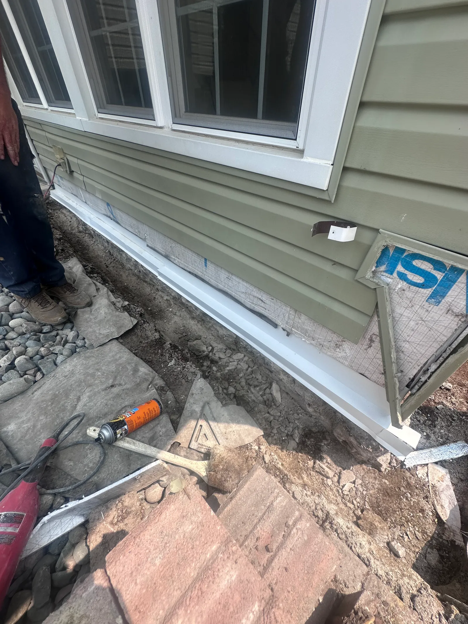 Close-up of excavated trench along home foundation revealing damage