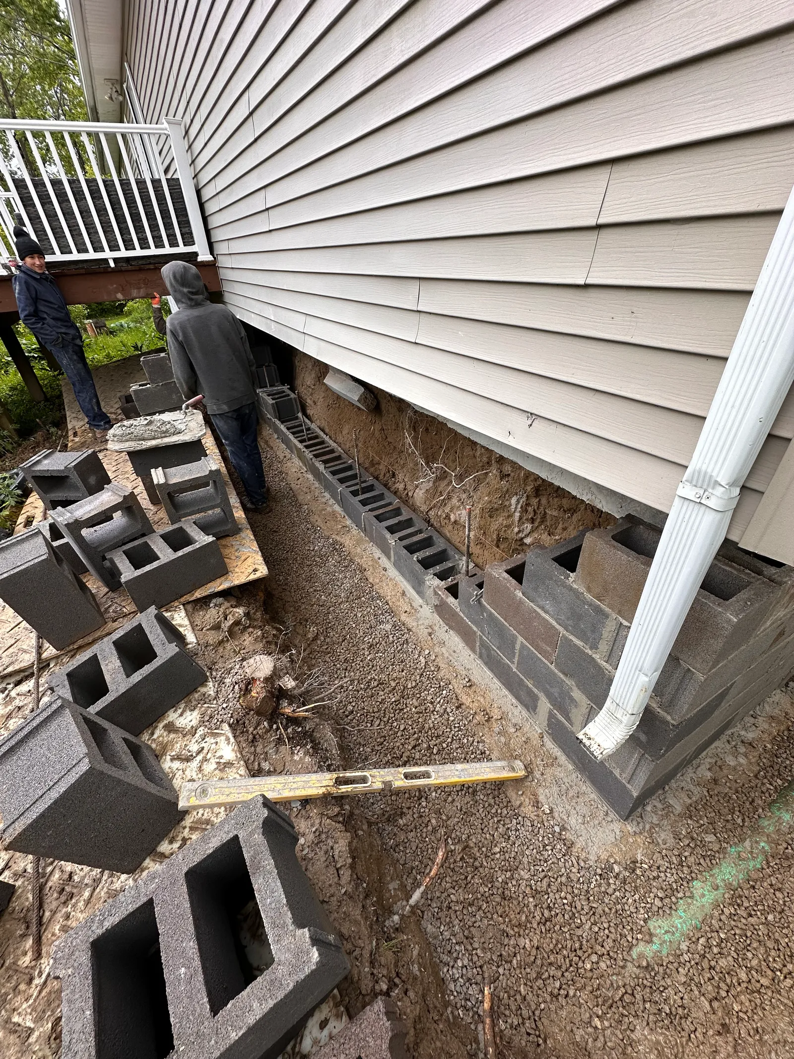 Worker constructing new CMU block foundation wall with spirit level check