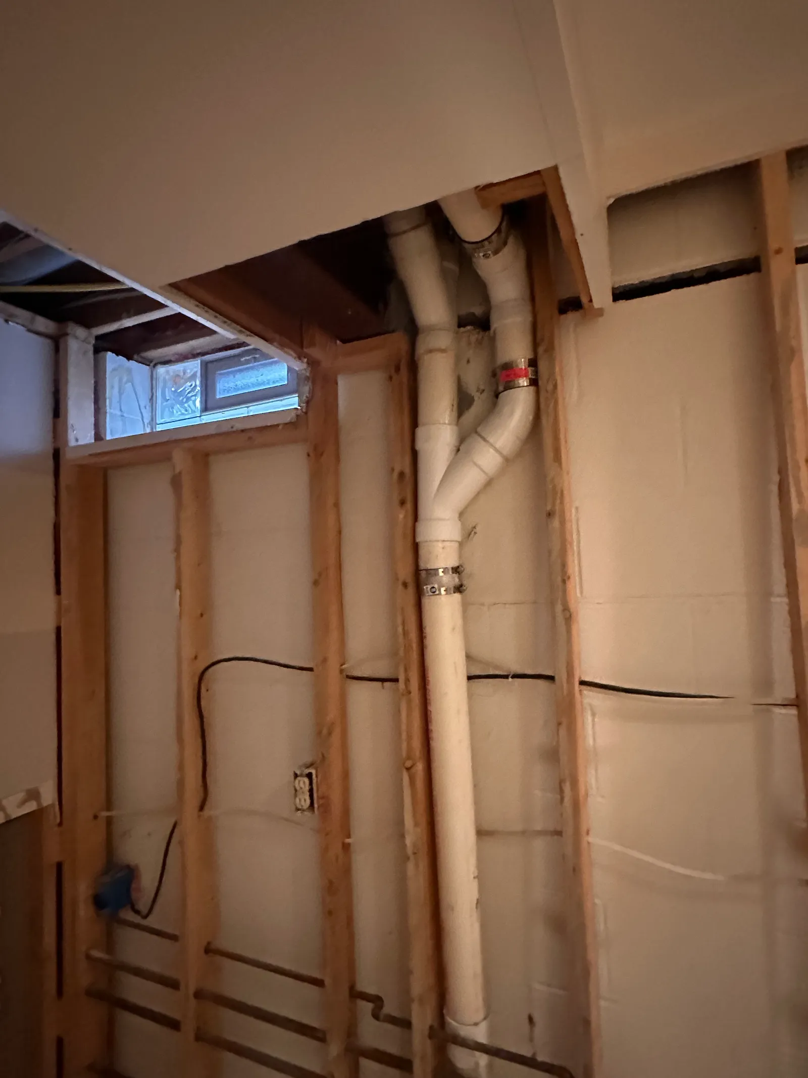 Corner detail of exposed block wall with plumbing and window during assessment